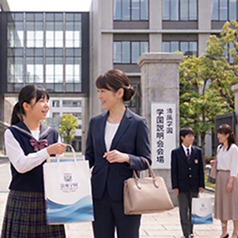 学校説明会の資料が入った紙袋を持ち、校門から出てくる親子