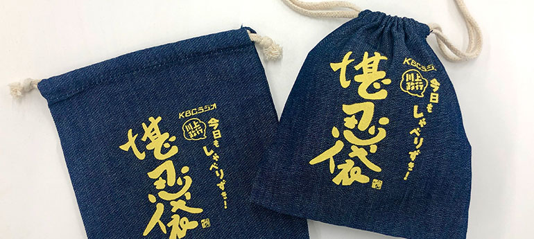 藍色の生地に薄い黄色で番組名が名入れ印刷されている、ラジオ番組のオリジナルノベルティグッズとして製作した、ダブル紐タイプのオリジナル巾着の実例画像