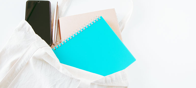 白色の生地のトートバッグにスマホ・ペン・ノートが収納されているイメージ画像