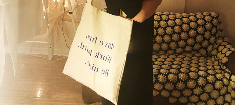 スクエア型トートバッグを肩に掛けた女性が写っている画像