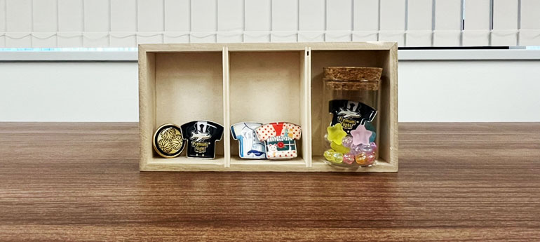 複数のデザインが異なるピンバッジをコルクボードに程よい間隔をあけて展示した画像