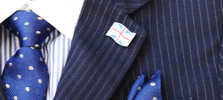 スーツの左胸のラペル部分のフラワーホールに、ユニオンジャックのピンバッジを装着している画像