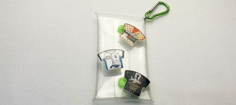 クリアポーチの中にシャツの形をした柄が異なる3種類のオリジナルピンバッジを収納した画像