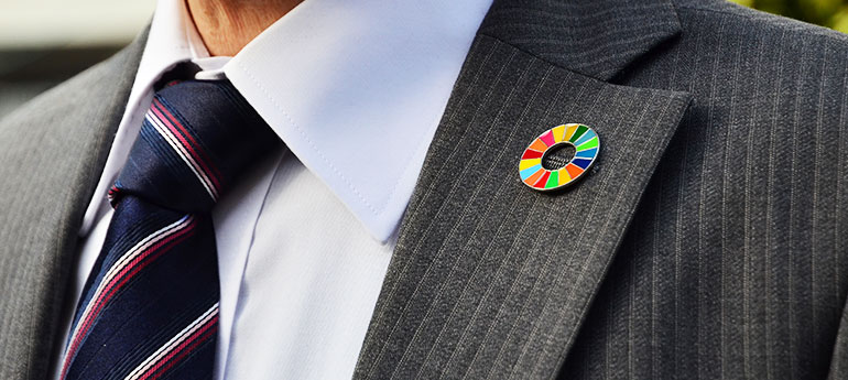 ピンズ・ブローチタイプのピンバッジ（ラぺルピン）を着けたスーツを着用している男性の画像