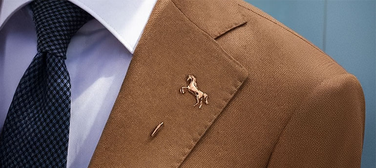 スティック・チェーンタイプのピンバッジ（ラぺルピン）を着けたスーツを着用している人の画像