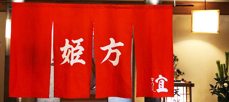 赤い生地の、4巾のれんの中央2巾に大きく「姫方」と名入れ印刷された、旅館の女湯の出入り口に掲げられたオリジナルのれんの実例画像