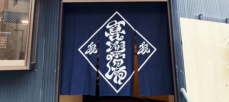 紺色の3巾のれんの中央に、白色でお店のオリジナルロゴが大きく名入れプリントされた、オリジナルのれんの実例画像