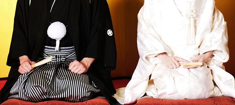 和装の結婚式(結納式)で正座で座っている新郎新婦がそれぞれ祝儀扇(末広)を手に持っているイメージ画像