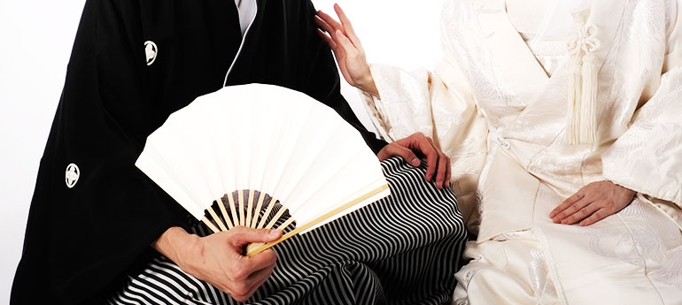 和装の結婚式で新郎や親族が使用する、扇面が白色の祝儀扇(末広)を持っている羽織袴の新郎のイメージ画像